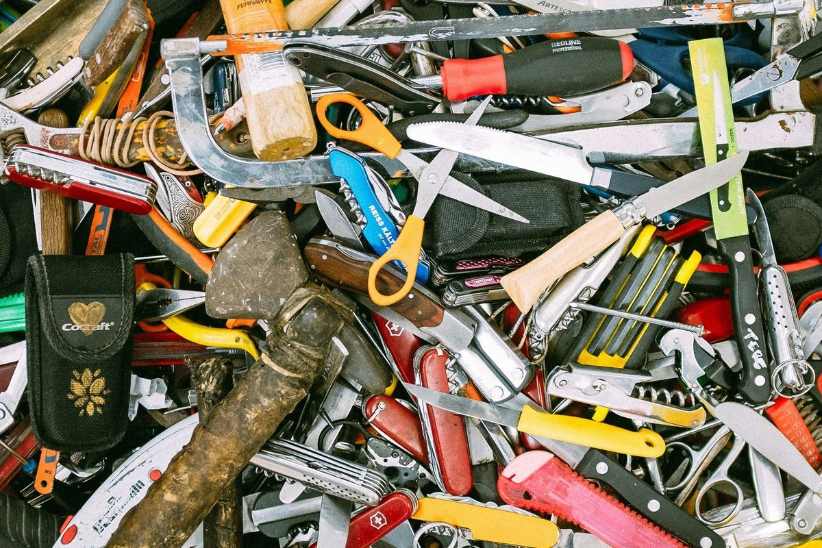 a cluttered pile of various hand tools and pocket knives