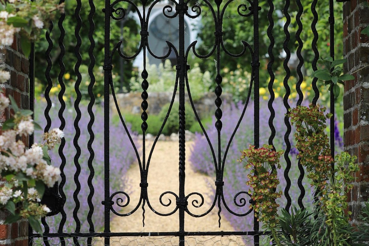 a wrought iron gate in the middle of a garden