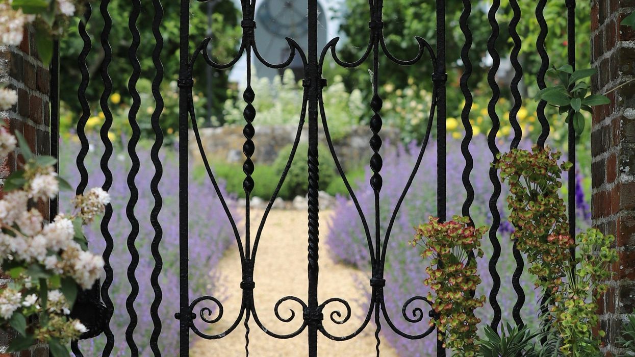a wrought iron gate in the middle of a garden