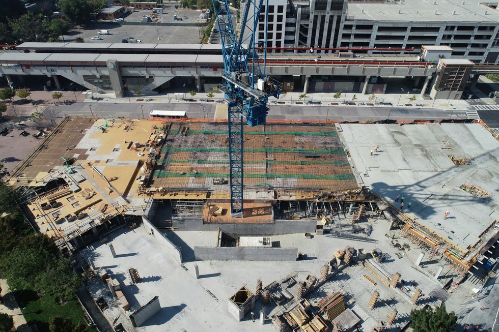 Aerial view of a construction site with a blue crane and partially built structure.