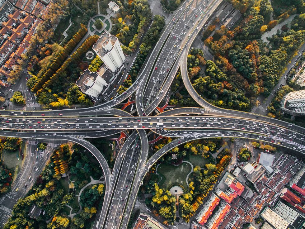 busy freeway interchange surrounded by trees and buildings, viewed from above
