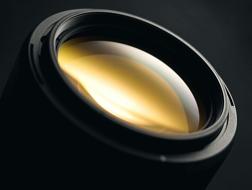 close-up of a camera lens with a golden reflection on the glass surface
