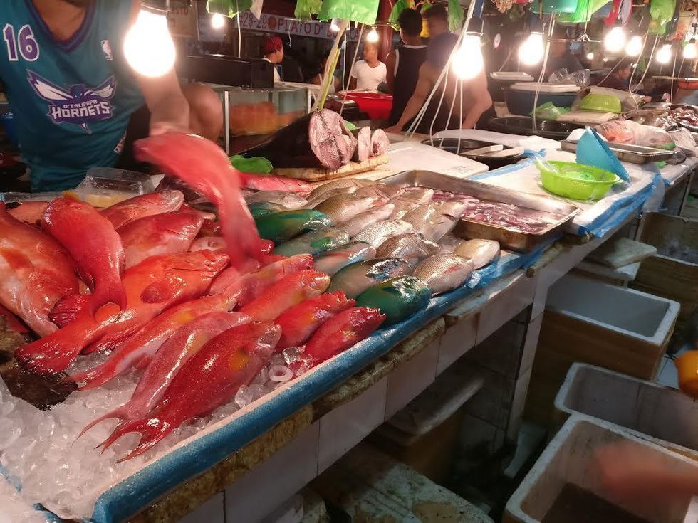 Fish displayed on ice at a bustling seafood market.