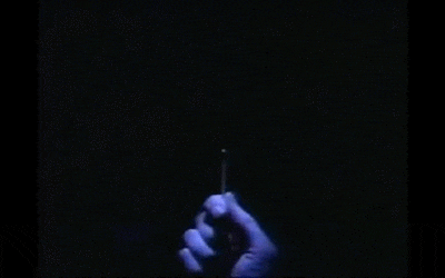 Hand holding a glowing matchstick in the dark.