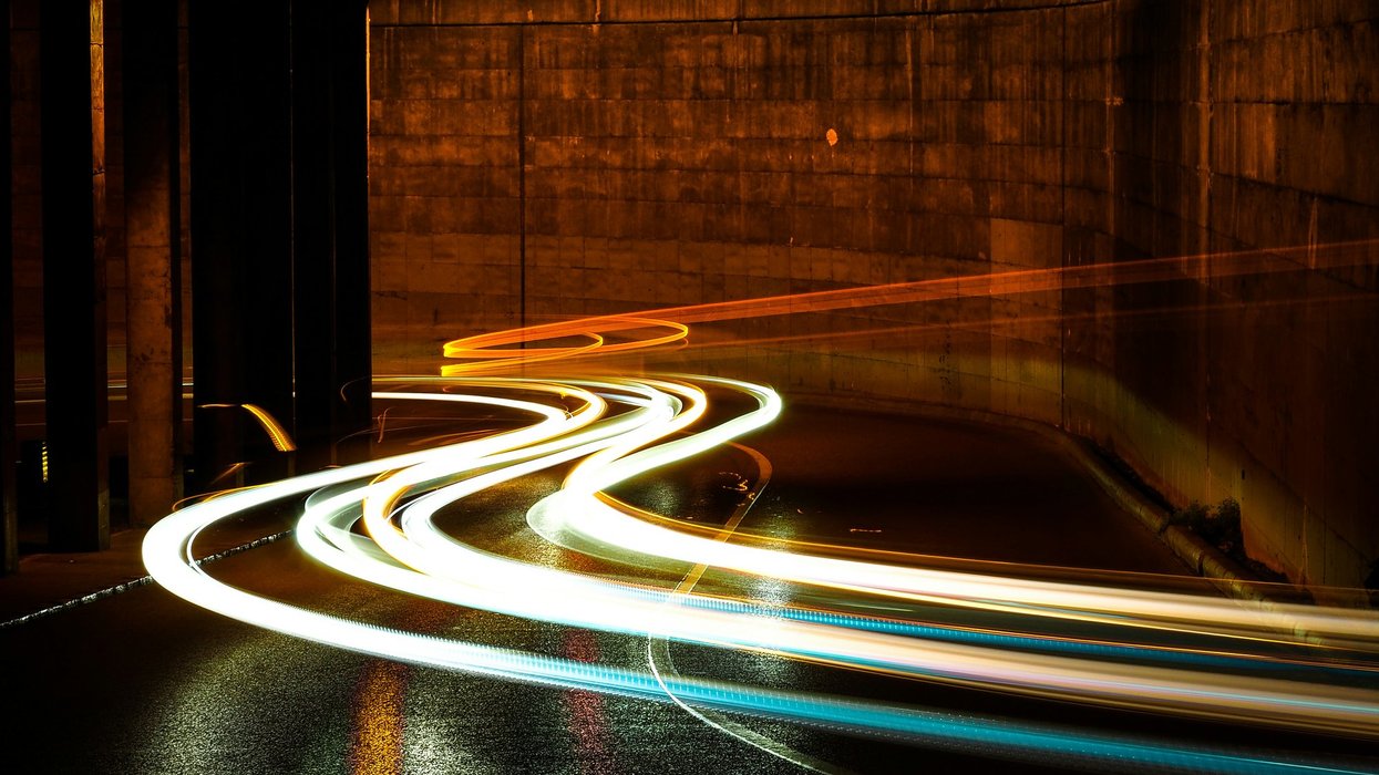 light trails curve in an illuminated tunnel at night