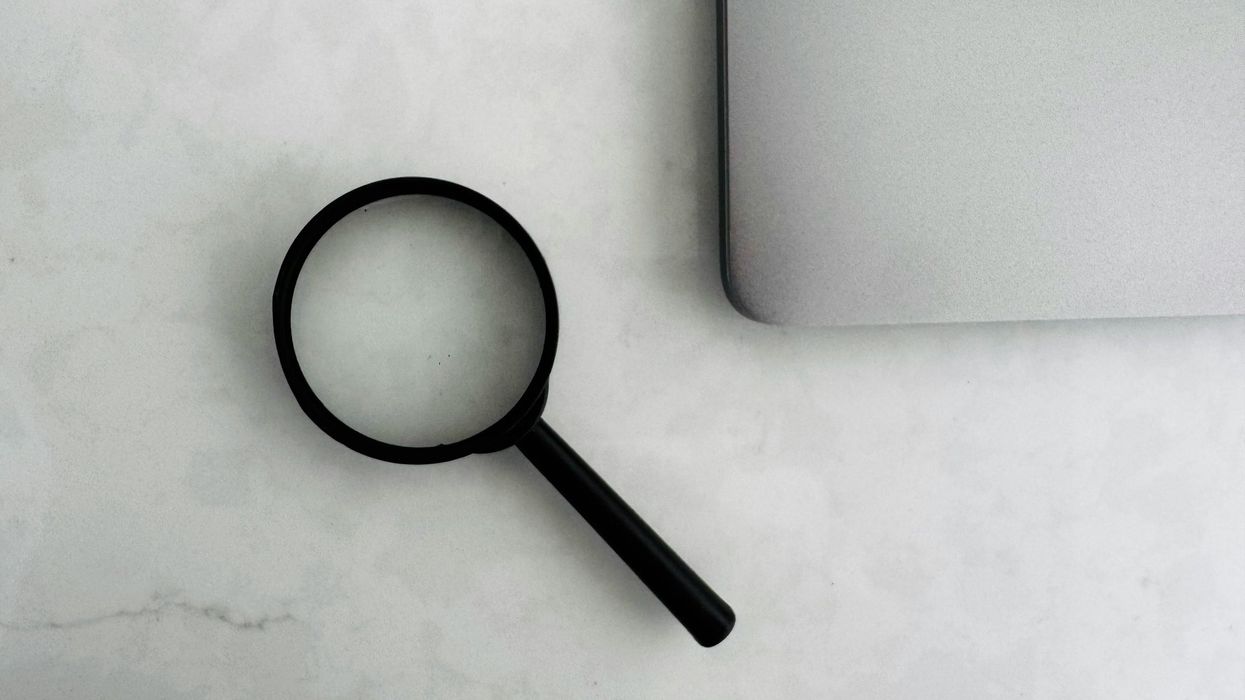 Magnifying glass sits near a laptop on a table.