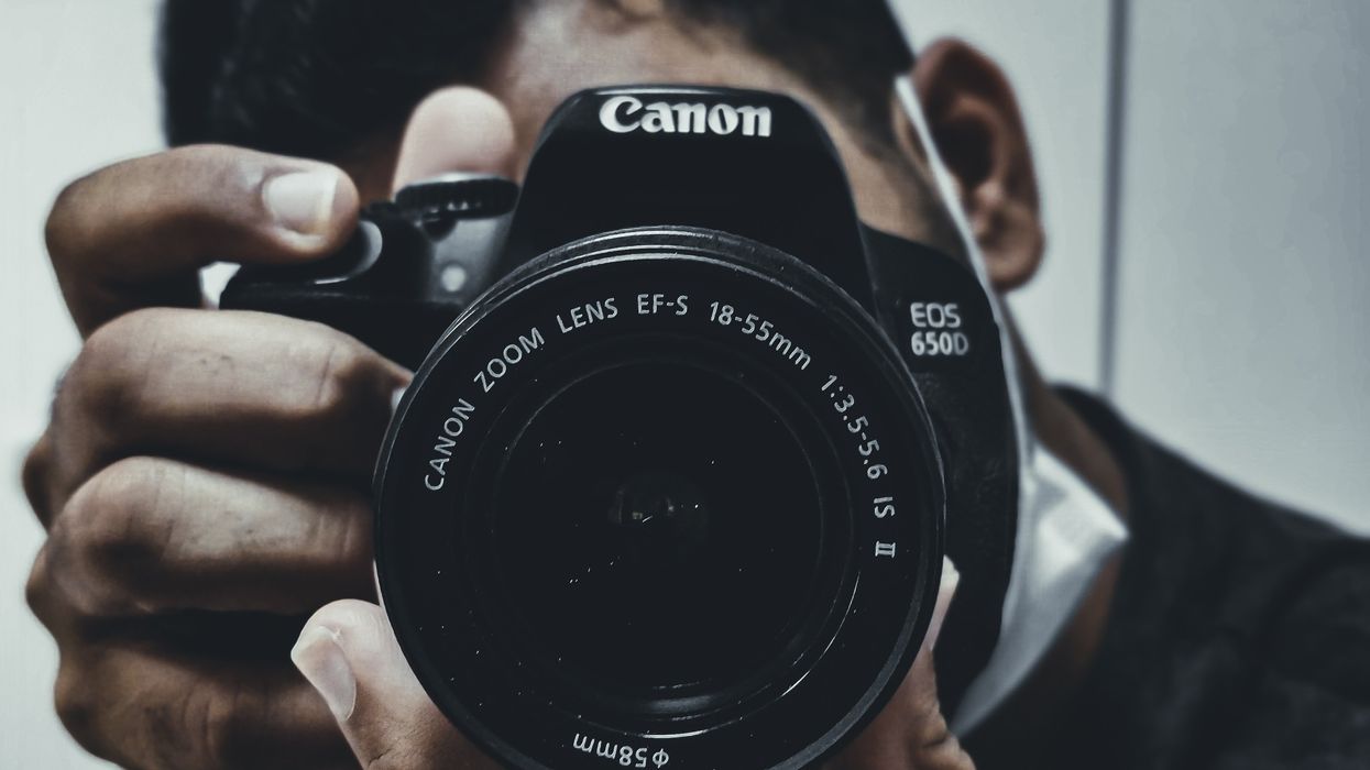 man holding black Canon DSLR camera to take photos