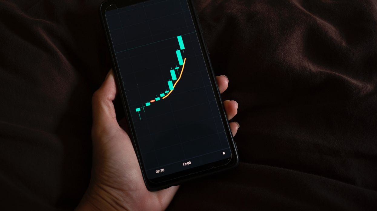 man holds phone showing chart with upward momentum