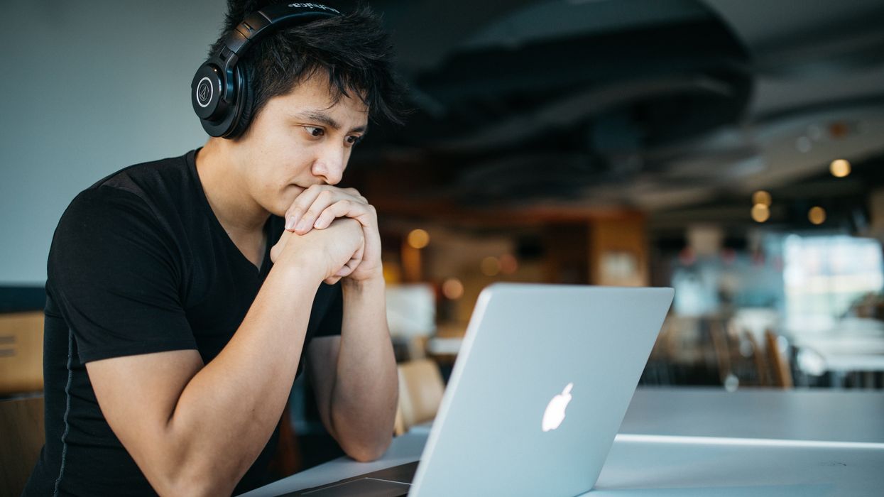 man wearing headphones studying AI tools in front of a MacBook