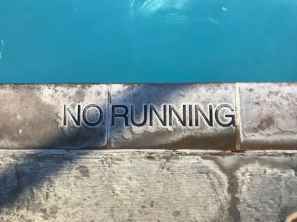 "No Running" warning on the edge of a swimming pool.