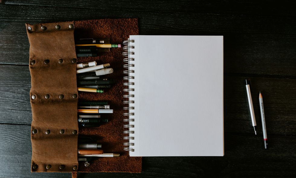open notebook with leather pen holder on a dark wooden table