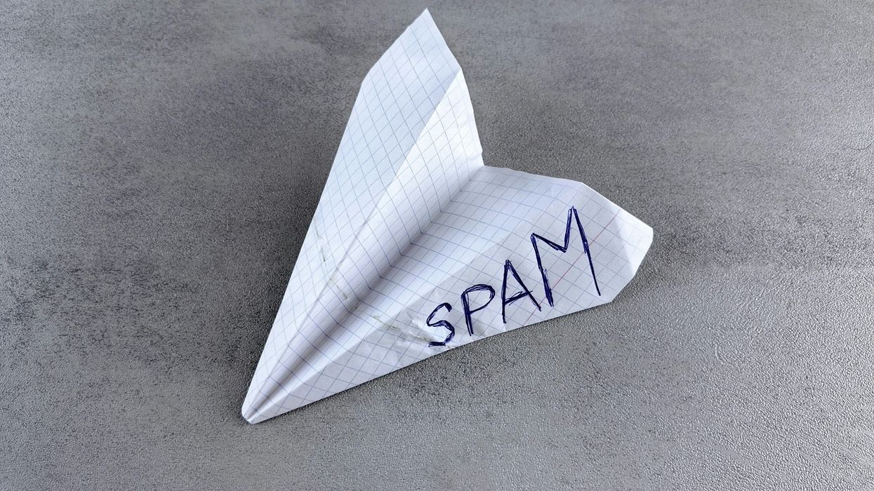 paper airplane with "SPAM" written on it, on a textured surface