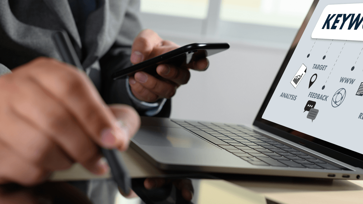 Person using phone and laptop with “Keyword” and icons on screen.