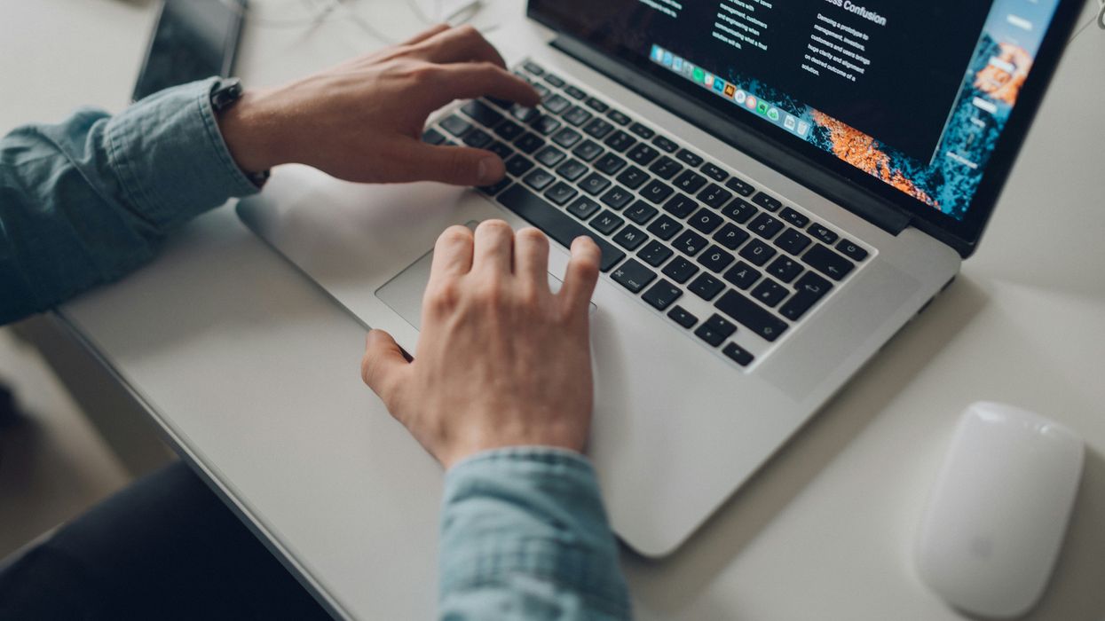 person wearing long-sleeve top working on laptop