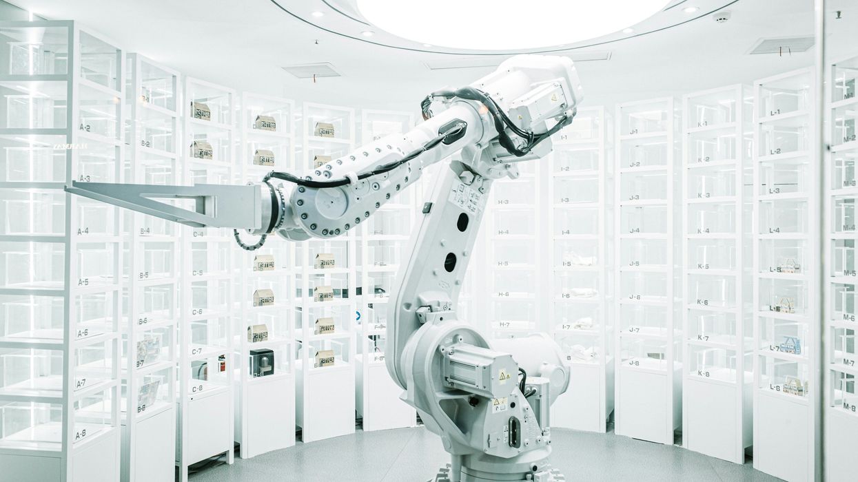 Robotic arm in a bright, futuristic laboratory with wall-mounted storage units.