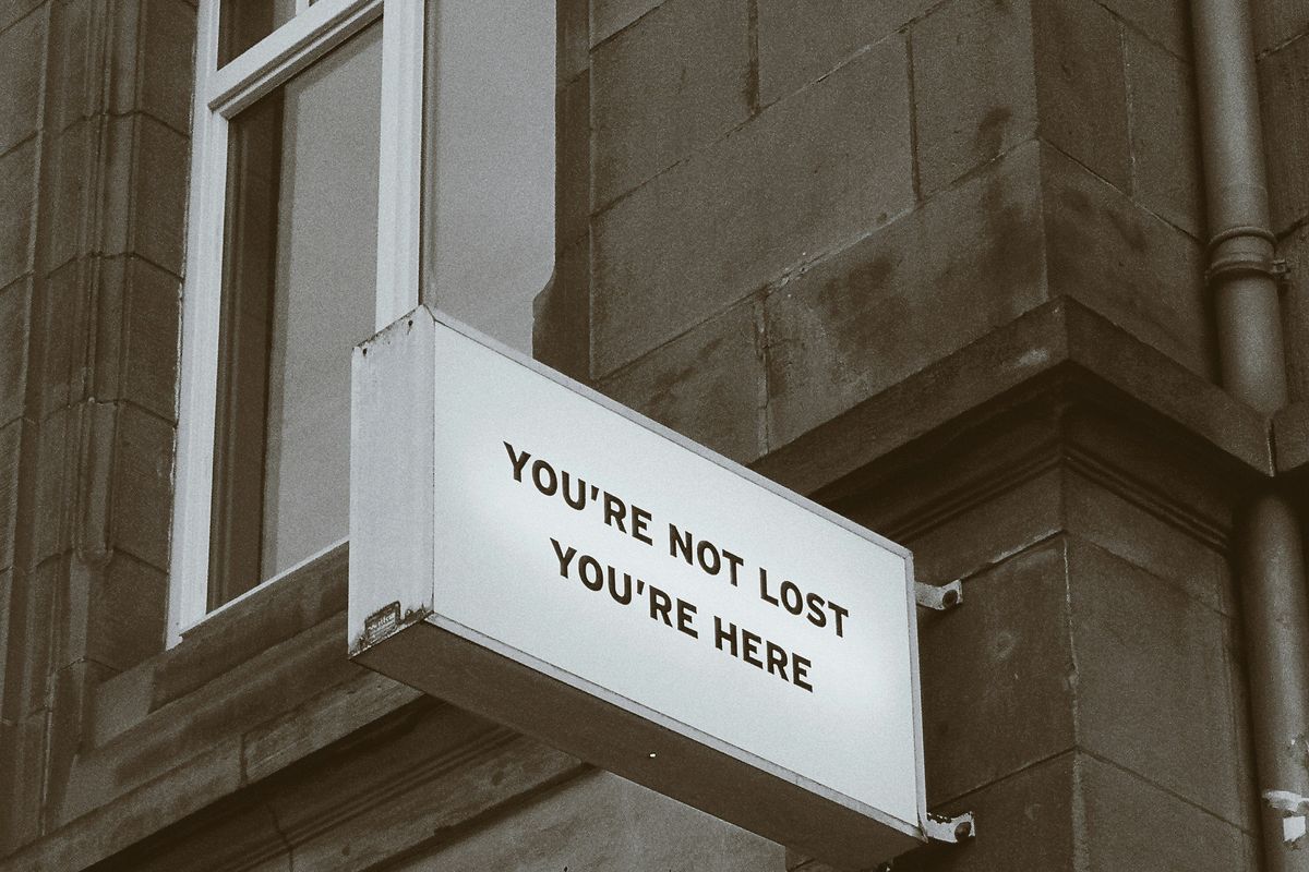 Sign on a building wall reads "YOU'RE NOT LOST YOU'RE HERE."