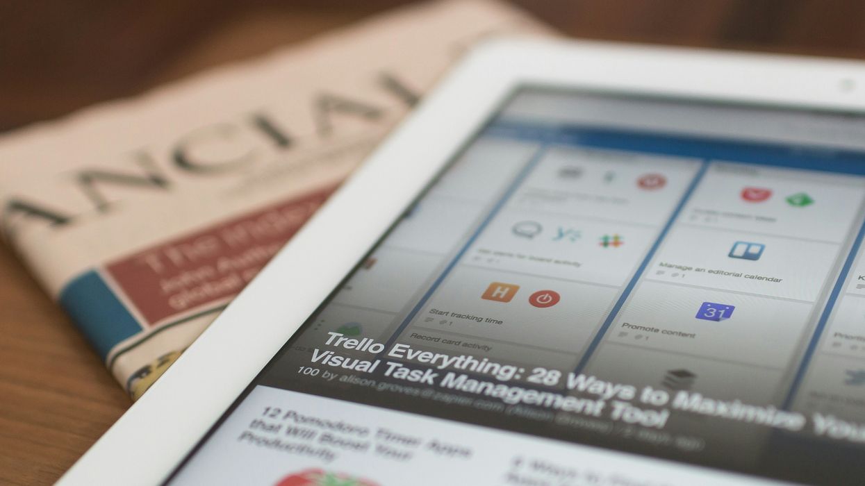 Tablet displaying Trello board next to a folded newspaper titled "Financial."
