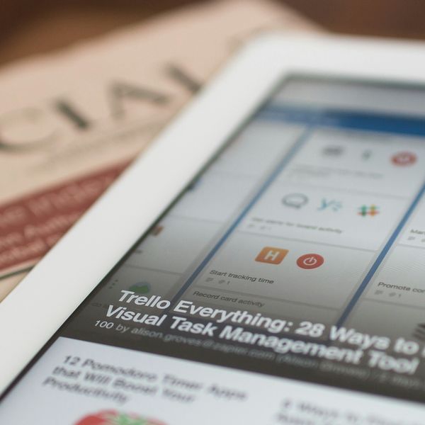 Tablet displaying Trello board next to a folded newspaper titled "Financial."
