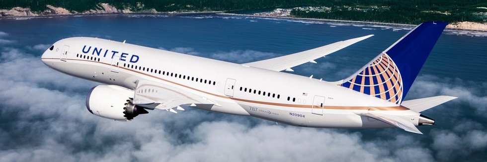 United airplane flying above clouds near a coastline.