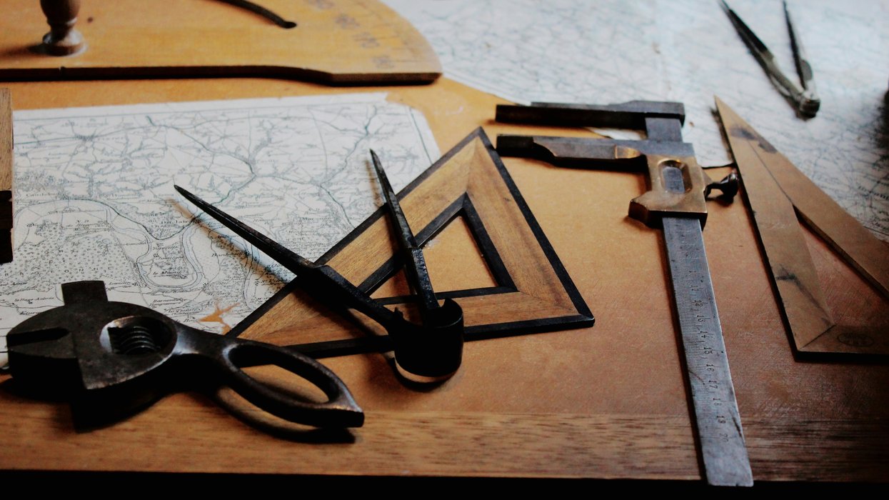 Vintage drafting tools and maps on a wooden table.