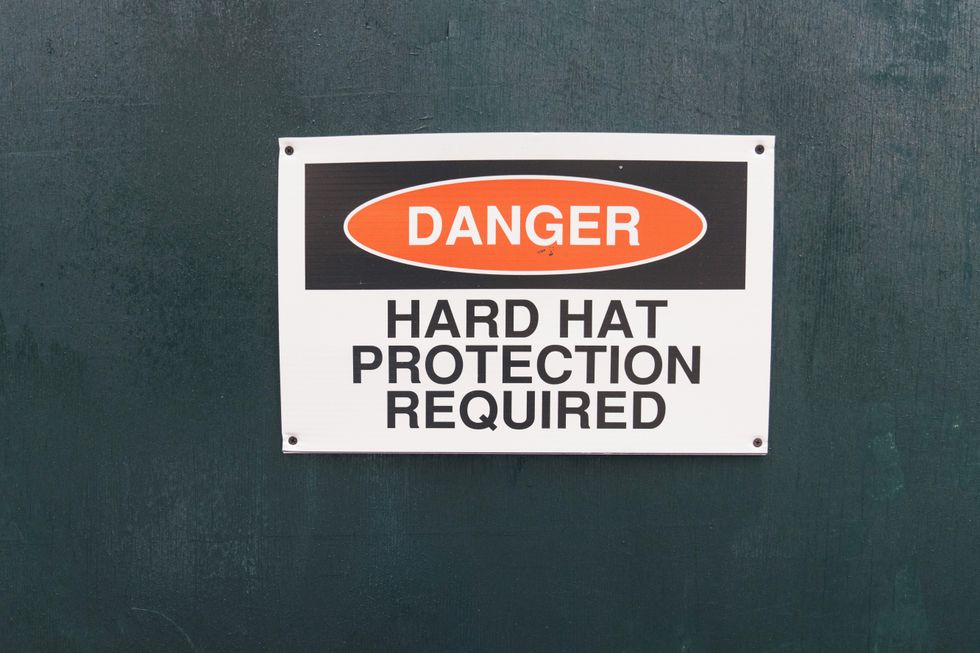 warning sign that says "danger, hard hat protection required" on a dark green background